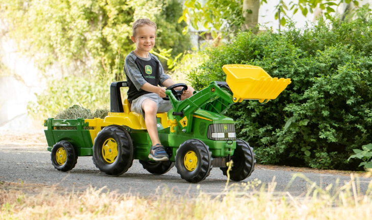 Boy riding on a Rolly Toy John Deere Tractor & Trailer