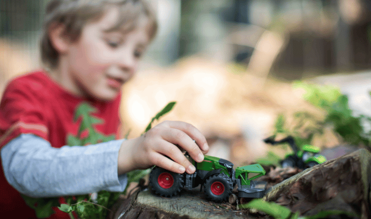 Boy playing with Siku toy tractor